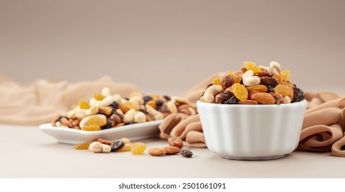 The mix of various nuts and raisins in a white bowl on a beige background. - Powered by Shutterstock