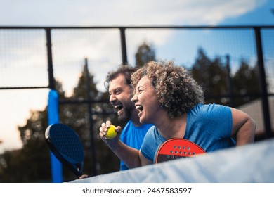 Mixed adult couple celebrate winning the point in padel on outdoor court. - Powered by Shutterstock