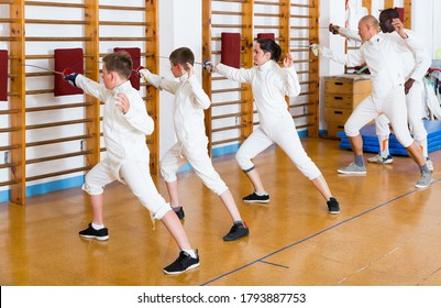 Mixed age group of athletes at fencing workout, training attack movements on mannequins - Powered by Shutterstock