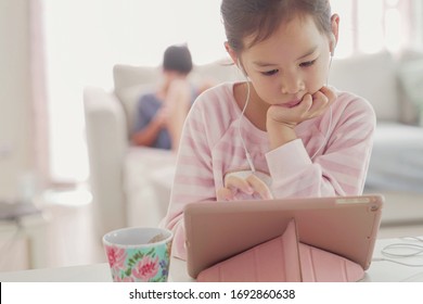 mixed Asian girl using digital tablet at home, listening to podcast, gaming, online education, elearning, homeschooling, social distancing, isolation, lockdown concept - Shutterstock ID 1692860638