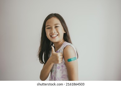 Mixed Asian Preteen Girl Showing Her Arm With Bandage After Got Vaccinated Or Inoculation, Child Immunization, Covid Omicron Vaccine Concept