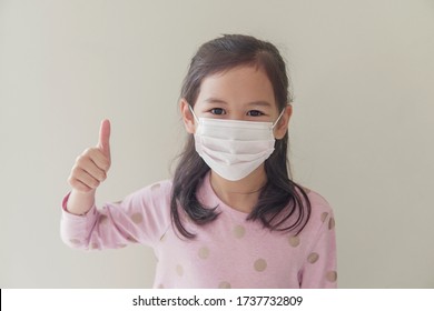 Mixed Asian Student  Girl Wearing Mask And Giving Thumb Up, School Reopening, Return Back To School After Delta  Covid-19 Pandemic Is Over, New Normal Concept