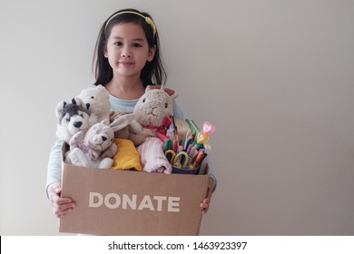 Mixed Asian Young Volunteer Girl Holding A Box Full Of Used Toys, Cloths, Books And Stationery For Donation, Happy Charity,Asian Community