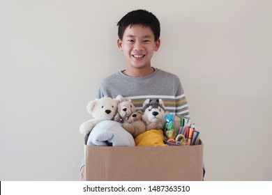 Mixed Asian Young Volunteer Preteen Teenage Boy Holding A Box Full Of Used Toys, Cloths, Books And Stationery For Donation, Asian Community