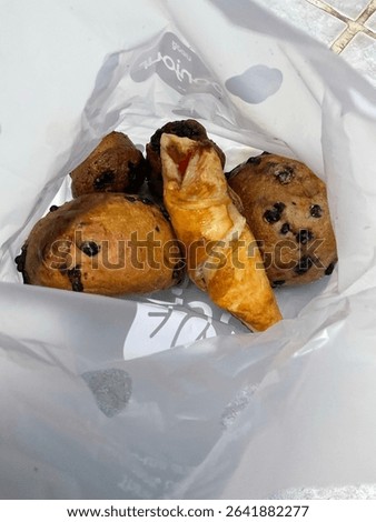 Mixed bread and pastry in a plastic takeout bag.
