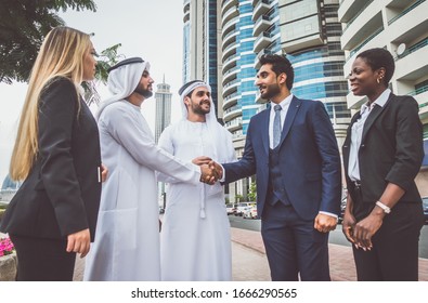 Mixed business team in Dubai. Business meeting with men wearing kandura and western people walking on the street