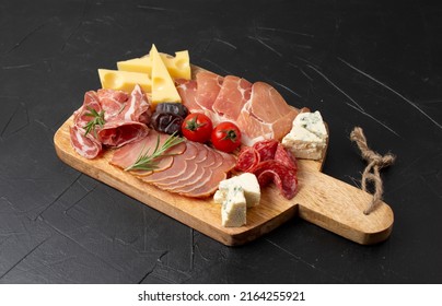 Mixed delicatessen with charcuterie and cheese board with a place for text. Italian appetizers or antipasto set with gourmet food on dark table - Shutterstock ID 2164255921
