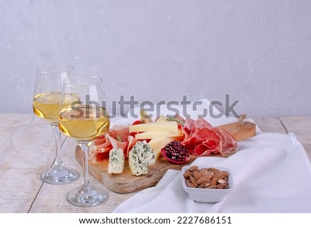 Mixed delicatessen and white wine with charcuterie and cheese board . Space for banner, logo, copy space. Italian appetizers or antipasto set with gourmet food on table