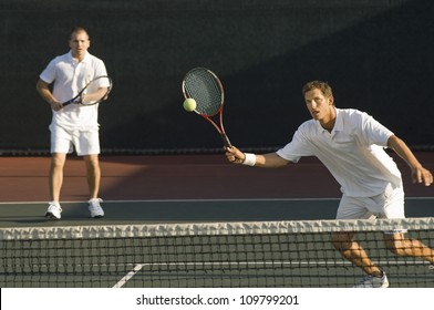 Mixed doubles player hitting tennis ball with partner in the background