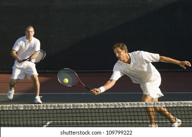 Mixed doubles player hitting tennis ball with partner in the background