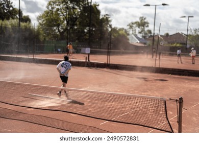 mixed doubles playing on a clay court at a local tennis club shaking hands at the net at the end of the match in spring - Powered by Shutterstock