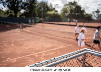 mixed doubles playing on a clay court at a local tennis club shaking hands at the net at the end of the match in spring - Powered by Shutterstock