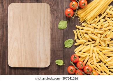 Mixed dried pasta selection and cutting board on wooden background. - Powered by Shutterstock