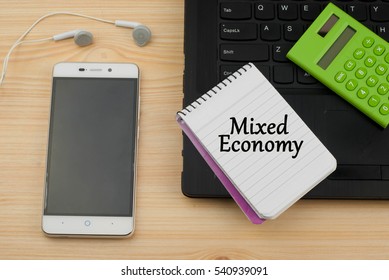 Mixed Economy Text Written On A Notebook. Wooden Background With Laptop,phone And Calculator. Business And Management Concept