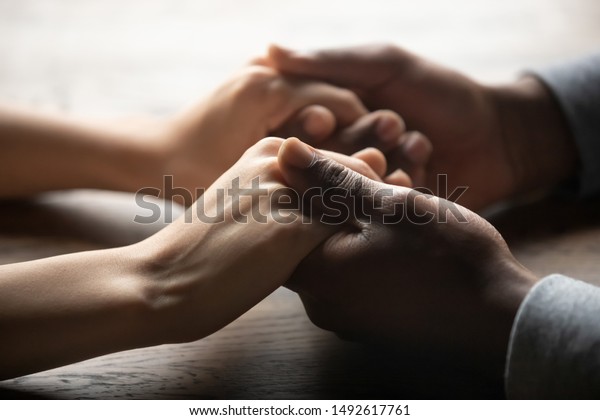 Mixed ethnicity family couple holding hands on\
table, black man friend husband support woman wife expressing love\
feelings, trust care honesty in interracial relationship concept,\
close up view