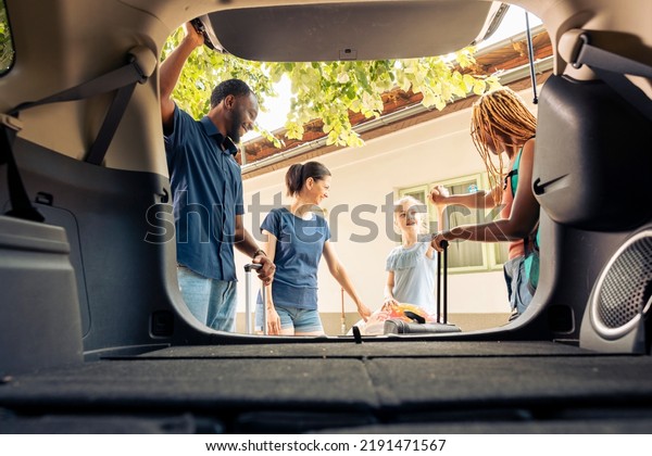 Mixed
family and friends travelling on vacation with vehicle, going on
summer holiday. Little girl with mother and young couple leaving
with automobile on road trip journey,
adventure.
