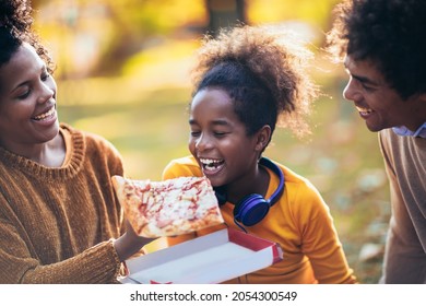 Mixed family having fun while picnicking in the park eating pizza. - Powered by Shutterstock