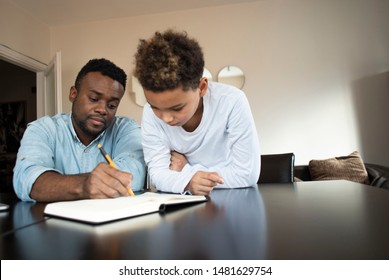 Mixed Family At Home. African Father And African American Child. Dad Helping Son With School Homework. Education And Relationship, Man Teaching And Boy Learning. Home Schooling.