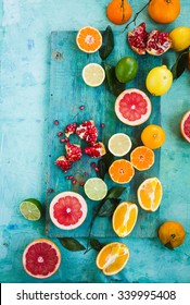 Mixed Festive Colorful Tropical And Citrus Fruit Sliced With Leaves Over Light Blue Tabletop. Pastel Rustic Style. 