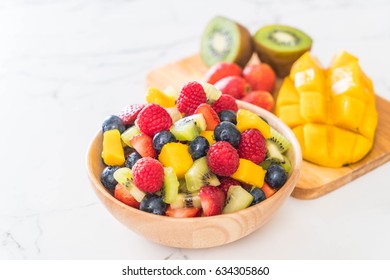 mixed fresh fruits (strawberry, raspberry, blueberry, kiwi, mango) on wood bowl - Shutterstock ID 634305860