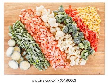 Mixed frozen vegetables on cutting board. Isolated on white background
