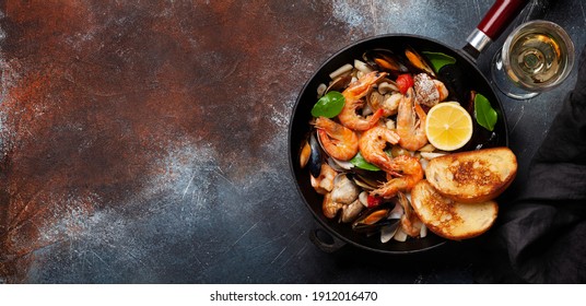 Mixed grilled seafood. Various roasted shrimps, mussels and shellfish in frying pan and white wine. Top view flat lay with copy space