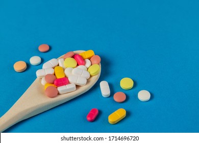 Mixed medicine pills, tablets on wooden spoon on blue background. Many different pills with space for text. Health care. Top view. Copy space. New image. Pharmaceutical picture. Closeup. Soft focus