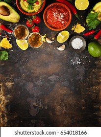 Mixed mexican food background. Party food. Guacamole,nachos, salsa, peppers, tomatoes, avocado and tequila shots on a rustic table. Space for text. Top view. Tex-mex cuisine. Assorted appetizers. 