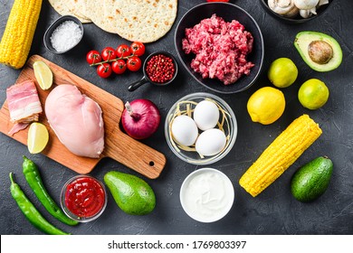Mixed mexican food background, raw organic ingredients for tacos with chicken and beef meat, corn tortilla, salsa, chilli over black background, top view.