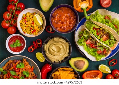 Mixed mexican food. Party food. Guacamole, nachos, fajita, meat tacos, salsa, peppers, tomatoes on a wooden table. Top view. Tex-mex cuisine. Assorted appetizers. Cuisine of Mexico