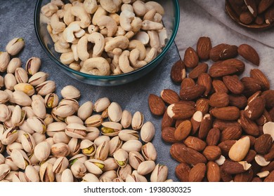 mixed nuts in ceramic bowls, wooden spoon. Almonds, walnuts, cashew nuts, pistachio nuts