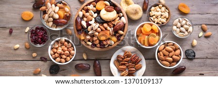 Mixed nuts and dried fruits in wooden bowl on wooden background, top view, banner. Healthy snack - mix of organic nuts and dry fruits.