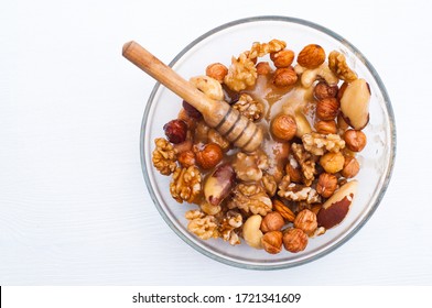 Mixed Nuts With Honey . Brazil Nuts, Walnuts And Hazelnuts On White Wooden Background. Healthy Food Concept. Vegetarian Food. Raw Food Concept