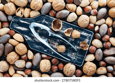 Mixed Nuts With Metal Nutcracker Arranged On Rustic Wooden Board Background