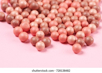 Mixed pink and tan colored glow face pearls blush close-up on pink background. Shallow DOF.