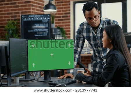 Mixed programmers analyze source code beside a green screen chroma key mockup, discussing algorithms, app development and online cloud computing in a server room.
