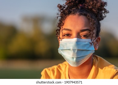 Mixed Race African American Biracial Teenager Teen Girl Young Woman Wearing A Face Mask Outside During The Coronavirus COVID-19 Pandemic