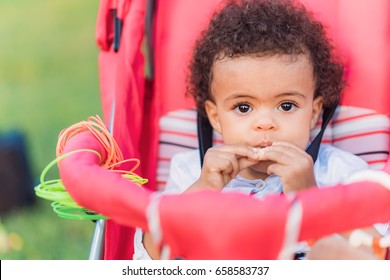 Mixed Race (african American And Caucasian) Baby Girl Eating A Cookie, Sitting In Her Trolley Chair