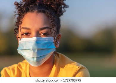 Mixed Race African American Teenager Teen Girl Young Woman Wearing A Face Mask Outside During The Coronavirus COVID-19 Virus Pandemic