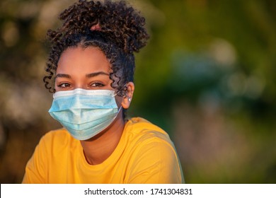 Mixed Race African American Teenager Teen Girl Young Woman Wearing A Face Mask Outside During The Coronavirus COVID-19 Virus Pandemic