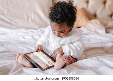 Mixed Race African Black Toddler Baby Girl Watching Cartoons On Tablet. Ethnic Diversity. Little Kid Child Using Technology. Early Age Education Development. Video Chat, Video Call.