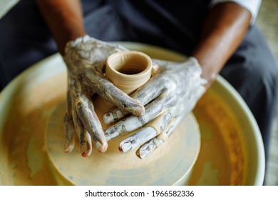 Mixed Race Afro Male Potter With Black Apron Sitting At Workshop Table Potter