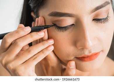 Mixed Race Asian Woman Putting Eye Liner On Eyelid On White Background