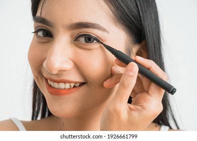 Mixed Race Asian Woman Putting Eye Liner On Eyelid On White Background