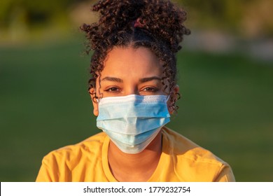 Mixed Race Biracial African American Teenager Teen Girl Young Woman Wearing A Face Mask Outside During The Coronavirus COVID-19 Pandemic