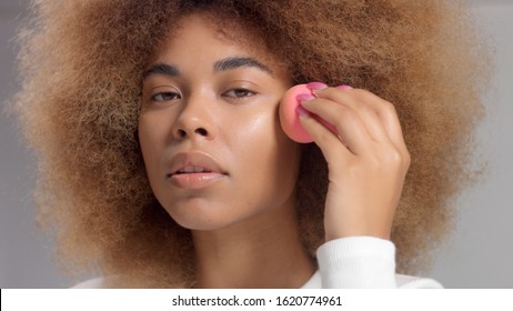 Mixed Race Black Woman With Big Afro Hair In Studio Put A Facial Makeup Base Foundation On Her Cheek Bone Woman Makes Up