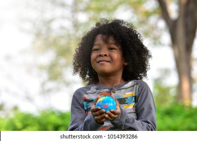 Mixed race boy holding Earth in hands against green background , Ecology concept.