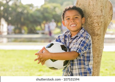 Mixed Race Boy Holding Soccer Ball in the Park Against a Tree.