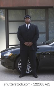Mixed Race Chauffeur Standing By Luxury Car