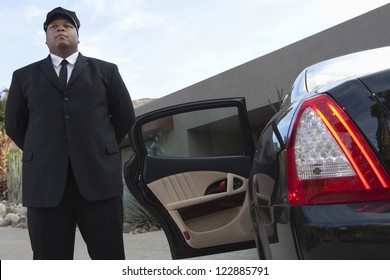 Mixed Race Chauffeur Standing By Luxury Car